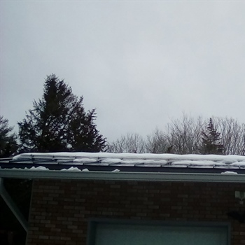 Snow-covered roof showcasing AceClamp metal roof ice guards effectiveness in Stonington.