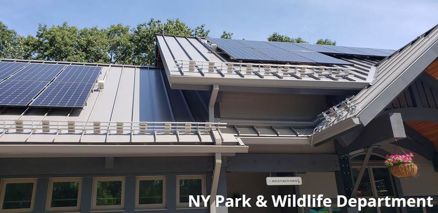 NY Parks and Wildlife project shows snow guards below solar panel installation on standing seam metal roof.
